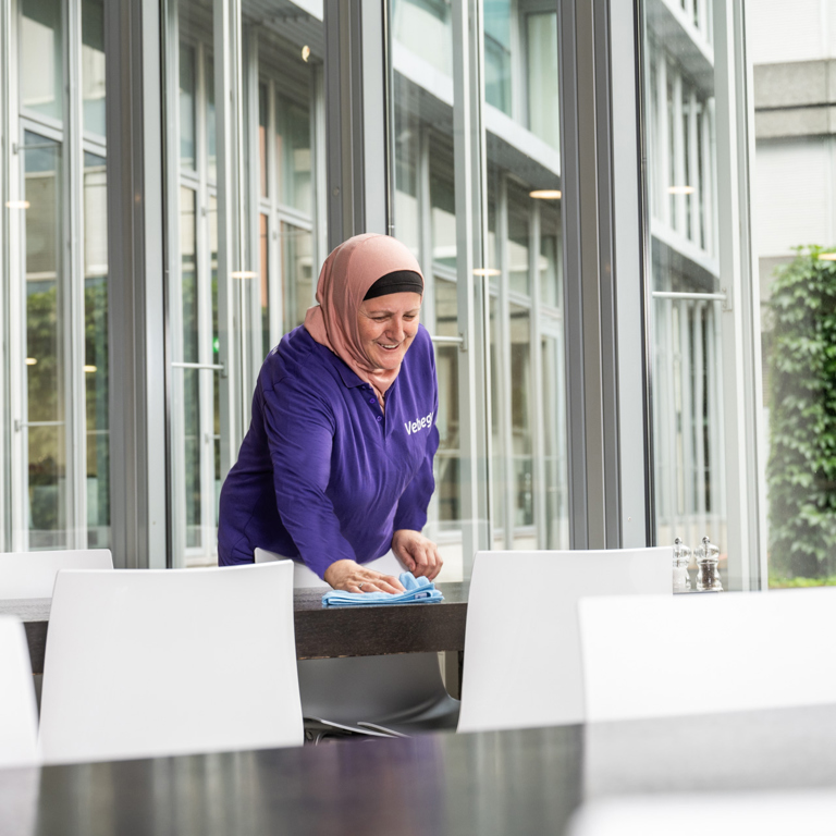 Een persoon maakt een tafel schoon in een openbare ruimte